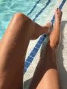 Young womanÃ¢â¬â¢s long tan legs in bright blue pool water